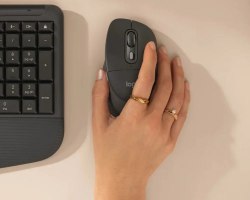 עכבר אלחוטי צבע אפור Logitech Signature Comfort Plus M850 Size L – יד אוחזת בפריט בודד בצבע אפור כהה לצד לוח מקשים אפור