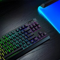מקלדת גיימינג מכנית אלחוטית Razer Blackwidow V4 Tenkeyless Hyperspeed – מקלדת שחורה עם תאורת RGB על שולחן כהה ומשטח מואר