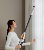 שואב אבק אלחוטי Deerma T10W – אישה מרימה את השואב הלבן והשחור כדי לנקות