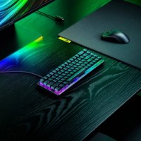מקלדת גיימינג מכנית Razer Huntsman V3 HE Magnetic Mini 65% 8KHZ – המקלדת מוארת ב-RGB על שולחן ליד עכבר