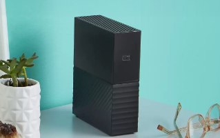 כונן כונן קשיח חיצוני Western Digital My Book 3 Essential 6TB – כונן קשיח שחור עומד על שולחן על רקע קיר טורקיז