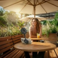 מאוורר ידני מגנטי צבע שחור Miracase MMHF120 – מאוורר שחור מחובר לטלפון נייד על שולחן עץ ליד אישה בחוץ סוללה נטענת