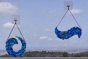 מובייל זכוכית בעבודת יד בגווני כחול וירוק בעיצוב גל תלוי מול חלון