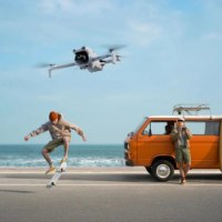 רחפן (DJI Lito X1 Fly More Combo (DJI RC 2 – מכשיר לבן טס מעל שני גברים רכב כתום וחוף ים