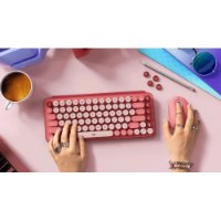 מקלדת מכאנית אלחוטית אדום/ורוד Logitech POP Keys – מונחת על שולחן ורוד כששתי ידיים מקלידות ומשתמשות בעכבר תואם