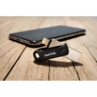 זיכרון נייד SanDisk iXpand Flash Drive Go 128GB – פריט בודד של כונן הבזק שחור-כסוף עם מחבר Lightning על שולחן עץ