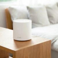 מגדיל טווח (3 באריזה) Tp-Link Deco X50 AX3000 WiFi 6 – יחידה לבנה בודדת מונחת על שולחן עץ בהיר ליד מיטה