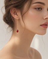 עגילי חוט גולדפילד 14K עם טיפת גארנט אדומה ענודים על אוזן של אישה, המציגים מראה נשפך ורומנטי.