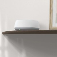 מערכת ביתית 2 יחידות בתקן Tp-Link Deco BE25 Mesh WiFi 7 – יחידה אלחוטית אחת לבנה ואפורה מונחת על מדף עץ עם נורית ירוקה