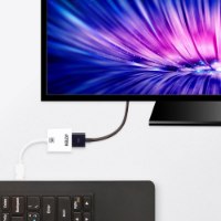 מתאם Aten VC986 DP to 4K-UHD HDMI Adapter – המתאם הלבן מחובר לכבל לבן ולצג המציג תמונה אבסטרקטית צבעונית