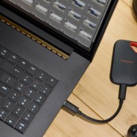 כונן SSD נייד SanDisk Extreme Portable Ssd V3 1TB – כונן שחור עם לולאה אדומה מחובר למחשב נייד בכבל USB-C 4K