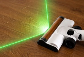 שואב אלחוטי חכם עם תאורת Deerma T20 Flip GreenVision – ראש השואב הלבן מציג קרן אור ירוקה על רצפת עץ מלוכלכת