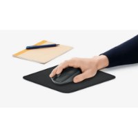 משטח לעכבר Logitech Graphite Mouse Pad – יד מניעה עכבר אפור על משטח שחור מחברת ועט מונחים ברקע