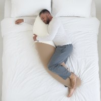 כרית גוף ארוכה התומכת בשינה המומלצת על הצד, מסייעת בהקלה ובמניעה של כאבי גב ואגן. עשויה מחומרי הגלם האיכותיים ביותר. אחריות לכל החיים. בתמונה: אישה שוכבת עם כרית גוף מלא BodyMoon בחיבוק וישנה 