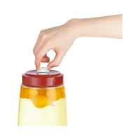 סט צנצנות אחסון צבע אדום Mira MJR-06 – יד לוחצת על השסתום הלבן במכסה האדום של צנצנת האחסון
