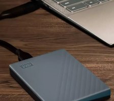 כונן קשיח חיצוני Western Digital WDBRMD0040BGY My Passport 4TB USB-C – בצבע אפור מחובר למחשב נייד על שולחן
