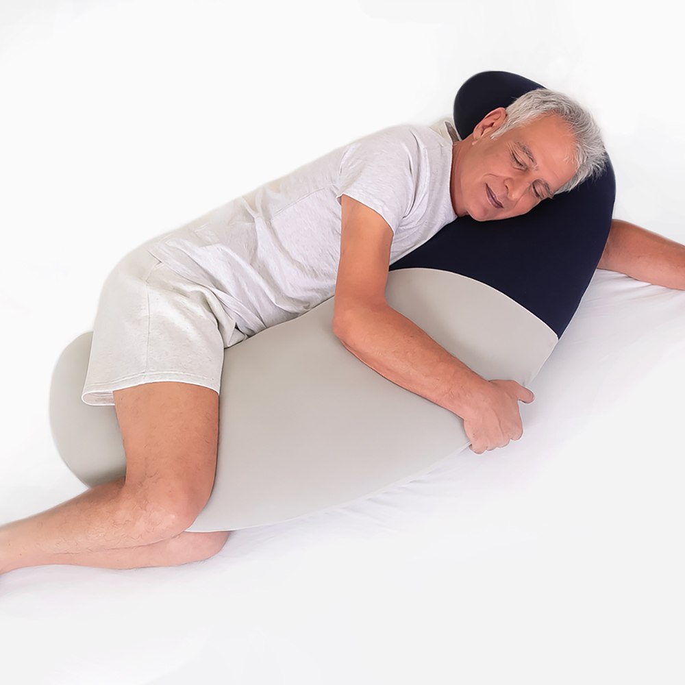 כרית גוף ארוכה התומכת בשינה המומלצת על הצד, מסייעת בהקלה ובמניעה של כאבי גב ואגן. עשויה מחומרי הגלם האיכותיים ביותר. אחריות לכל החיים. בתמונה: גבר שוכב עם כרית גוף מלא BodyMoon בחיבוק וישן