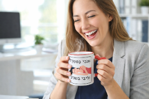 ספלים הומוריסטיים ספל קרמי עם ידית לב בצבע אדום, איור של אישה ישנה וכיתוב: אנכי במשרד וליבי בשנ"צ