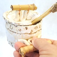 כלי דבש קרמי  בשילוב ענפי עץ טבעיים ומקל דבש תואם