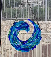 מובייל זכוכית בעבודת יד בגווני כחול וירוק בעיצוב גל תלוי מול חלון