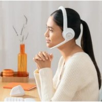 אוזניות אלחוטיות צבע שחור Logitech Zone 300 – אישה חובשת סט ראש לבן עם מיקרופון יושבת ליד שולחן עבודה