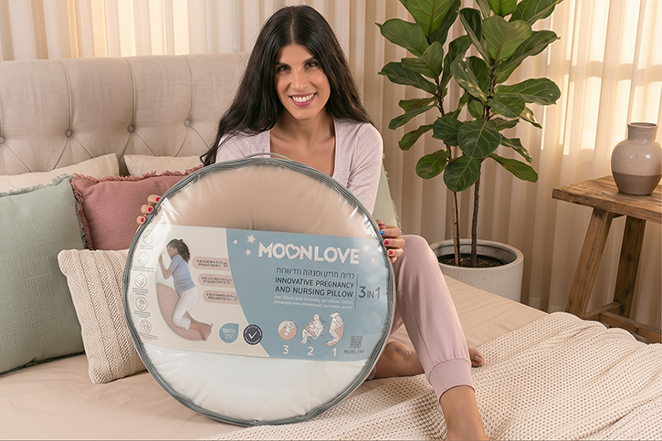אישה בהריון מחזיקה אריזה עם כרית הריון והנקה MoonLove